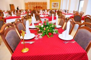 a dining room with red tablecloths and flowers on tables at DAR AMMAR in El Jem