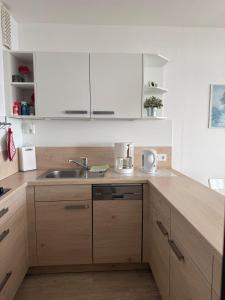 a kitchen with white cabinets and a sink at Strandhotel Wohnung 30 in Dahme +11 photos