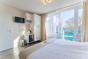 a bedroom with a large bed and a large window at Hotel Kijkduin in Domburg