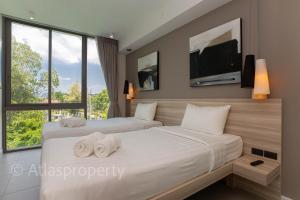 two beds in a bedroom with a tv on the wall at Oceanstone- 2BDR apartment in Ban Thalat Choeng Thale