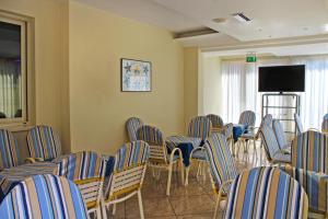 a room with chairs and a flat screen tv at Hotel Royal in Misano Adriatico