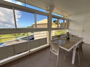 a dining room with a table and some windows at Appartement tout confort et idéalement situé in Petit-Bourg