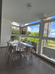 a dining room with a table and chairs and windows at Appartement tout confort et idéalement situé in Petit-Bourg