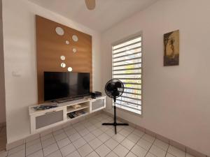 a living room with a flat screen tv and a fan at Appartement tout confort et idéalement situé in Petit-Bourg