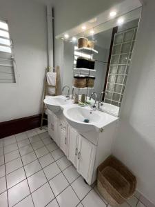 a white bathroom with a sink and a mirror at Appartement tout confort et idéalement situé in Petit-Bourg +6 photos