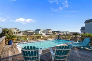 a swimming pool with two chairs and a deck at Ocean Views with Heated Pool One Row from Beach in Oak Island