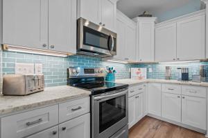 a kitchen with white cabinets and a stove top oven at Ocean Views with Heated Pool One Row from Beach in Oak Island