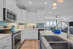 a kitchen with white cabinets and stainless steel appliances at Ocean Views with Heated Pool One Row from Beach in Oak Island