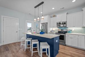 a kitchen with white cabinets and a blue island with stools at Ocean Views with Heated Pool One Row from Beach in Oak Island +64 photos