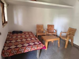 a room with two chairs and a bed and a table at Virendra Home Stay in Kartal +4 photos