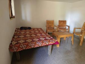 a bedroom with a bed and two chairs and a table at Virendra Home Stay in Kartal