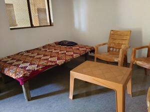 a bed with a table and a chair in a room at Virendra Home Stay in Kartal