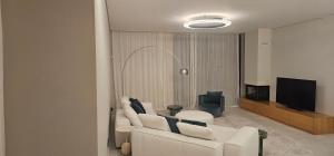 a living room with a white couch and a television at Villa Anjos - Luxury Villa with Infinity Pool & Ocean View in Canhas