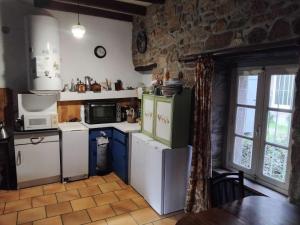 a kitchen with white appliances and a stone wall at Face à la Mer in Perros-Guirec