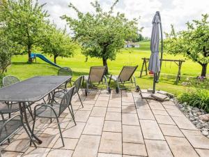a patio with a table and chairs and an umbrella at Ferienhof Rummel Allgäu - verschiedene Unterkünfte für bis zu 6 Personen - Sauna, Spielplatz, Lagerfeuer & Frühstücksservice - ideal für Familien- und Aktivurlaub in Argenbühl