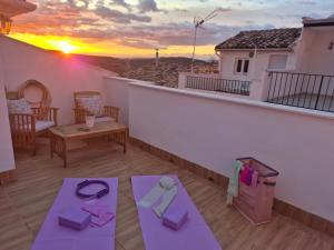a balcony with purple yoga mats and a sunset at Casa Papel y Pluma in Cazorla