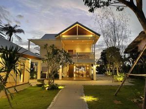 a large yellow house with a porch and a driveway at Villa Baan Loukpla in Hua Hin