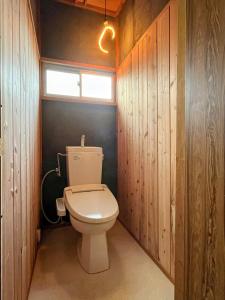 a bathroom with a toilet with wooden walls and a window at Maison N in Shimoda