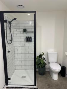 a bathroom with a toilet and a shower with a glass door at Modern Soho Pad with Sunny Deck in West Hobart