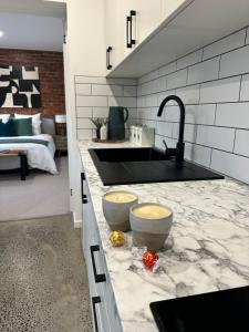 a kitchen with a sink and two bowls on a counter at Modern Soho Pad with Sunny Deck in West Hobart +9 photos