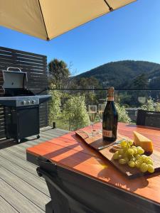 a bottle of wine and grapes on a wooden table at Modern Soho Pad with Sunny Deck in West Hobart