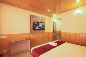 a bedroom with a bed and a tv on the wall at The Himvan Stay in Mundaghat  +32 photos