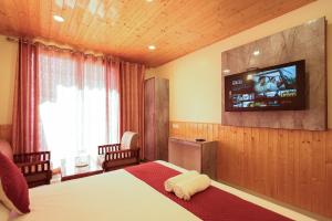 a bedroom with a bed with a television on the wall at The Himvan Stay in Mundaghat 