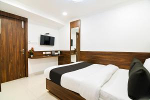 a hotel room with a bed and a television at Super Hotel O Eminent Hotel in Kolkata