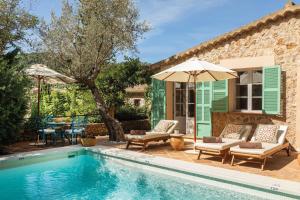 a pool with chairs and umbrellas next to a house at La Residencia, A Belmond Hotel, Mallorca in Deia