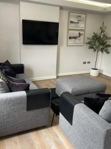 a living room with two couches and a flat screen tv at Riverview Apartment 2 in Matlock