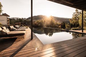 a view of a pool from a house with the sun setting at DER MESNERWIRT - 4 Superior - Meraner Land in Avelengo