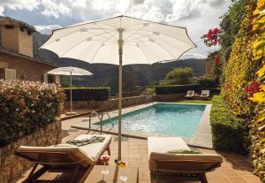 a pool with an umbrella and two chairs and a table and a pool at La Residencia, A Belmond Hotel, Mallorca in Deia