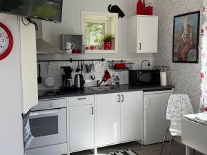a white kitchen with white cabinets and a sink at Grottstugan in Ljungskile