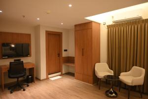 a room with a desk and a television and chairs at Brahmaputra Manor in Tezpur +15 photos