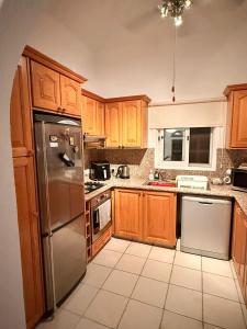 a kitchen with wooden cabinets and a stainless steel refrigerator at Luxury 3Bedroom Villa with Pool, Garden & Sunset in Tala