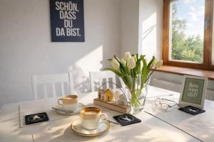 a table with two cups of coffee and a vase of flowers at Cozy Home in Schramberg