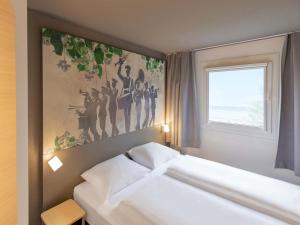 a bedroom with two beds and a painting on the wall at B&B HOTEL Gießen-Linden in Gießen