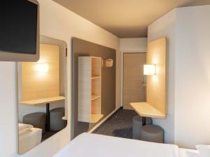 a bedroom with a bed and a tv on a wall at B&B HOTEL Gießen-Linden in Gießen
