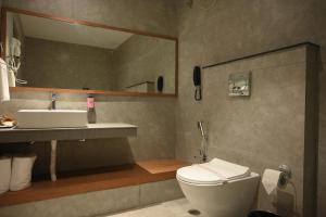 a bathroom with a sink and a toilet and a mirror at Brahmaputra Manor in Tezpur