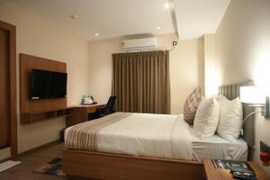 a hotel room with a bed and a television at Brahmaputra Manor in Tezpur