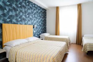 a bedroom with two beds and a wall with triangles at Aparthotel Manolita in Rimini