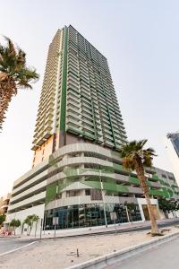a tall building with a palm tree in front of it at Tranquil Wellness Tower By Wellcube in Dubai