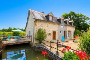 a house with a bridge next to a river at Le mouly/petit gite in Miossens-Lanusse