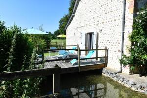 a house with a deck with chairs on the water at Le mouly/petit gite in Miossens-Lanusse