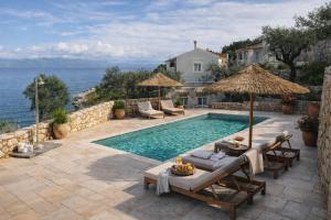 a pool with chairs and umbrellas next to the ocean at Paxos Sunrise Villas in Gaios