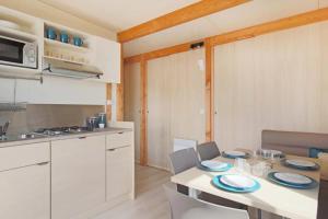 a kitchen with a table and chairs in a kitchen at Camping 3 étoiles - ccbfggd in Lepin-le-Lac