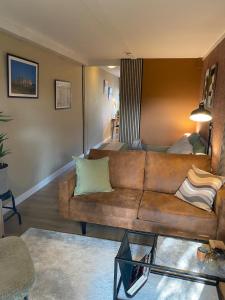 a living room with a brown couch and a bed at Appartement met jacuzzi in Huizen in Huizen