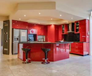 a red kitchen with a bar with stools at Home in Highton in Highton