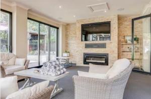 a living room with white furniture and a fireplace at Home in Highton in Highton