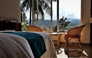 a bedroom with a bed and chairs and a large window at The Villa Rochelle Kandy in Kandy